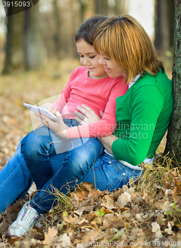 Image of Mother is reading from tablet with her daughter