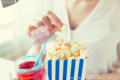 Image of woman eating popcorn with drink in glass mason jar