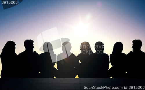 Image of silhouettes of friends sitting on stairs over sun