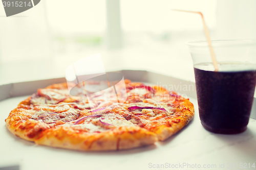 Image of close up of pizza with cola on table