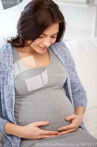 Image of happy pregnant woman sitting on sofa at home