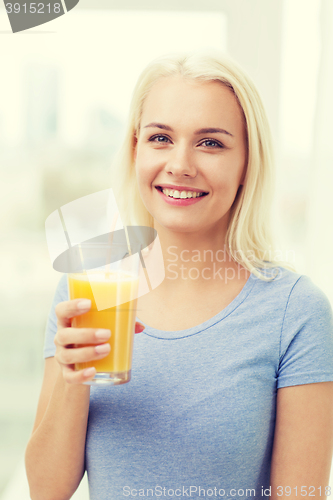 Image of smiling woman drinking orange juice at home