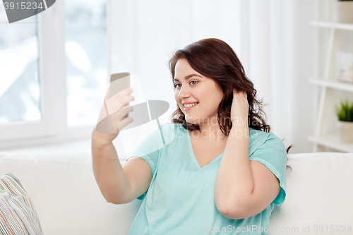 Image of happy plus size woman with smartphone at home