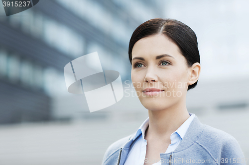 Image of young smiling businesswoman over office building