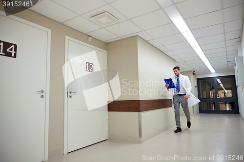 Image of doctor with clipboard walking along hospital