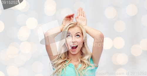 Image of happy smiling young woman making bunny ears