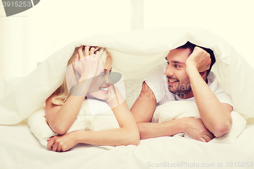 Image of happy couple lying in bed and talking at home