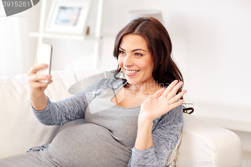 Image of happy pregnant woman with smartphone at home