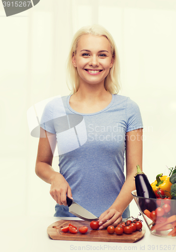 Image of smiling young woman chopping vegetables at home