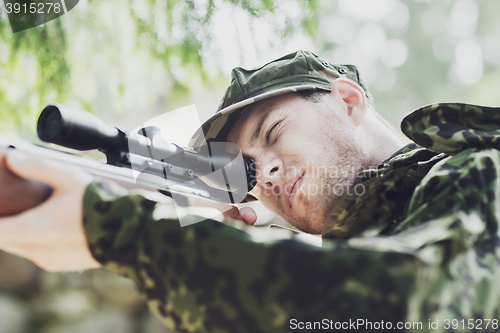 Image of young soldier or hunter with gun in forest