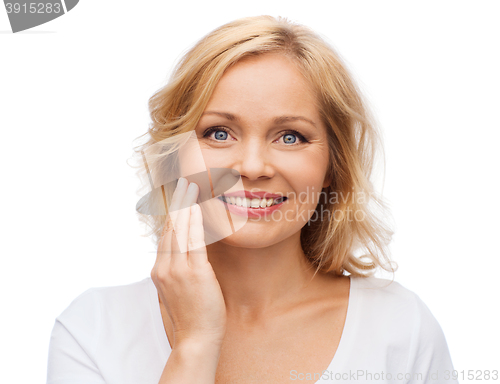 Image of smiling woman in white t-shirt touching her face