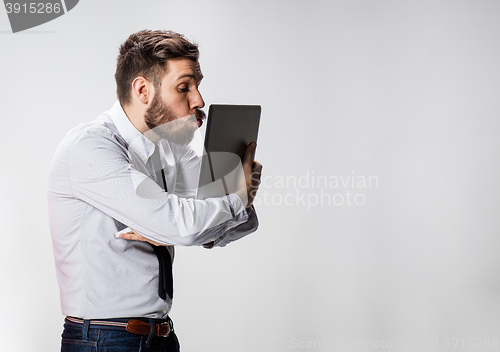 Image of The young businessman with laptops kissing screen on gray background