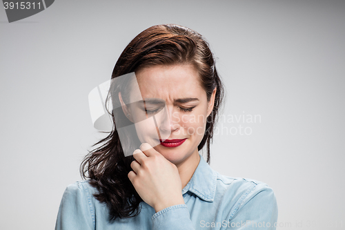 Image of The portrait of a crying young lonely woman on gray