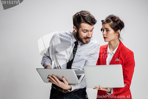 Image of The young businessman and businesswoman with laptops communicating on gray background