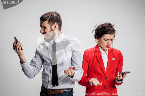 Image of Business concept. The two young colleagues holding mobile phones on gray background