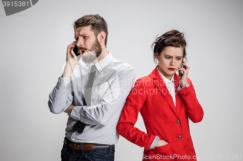 Image of Business concept. The two young colleagues holding mobile phones on gray background