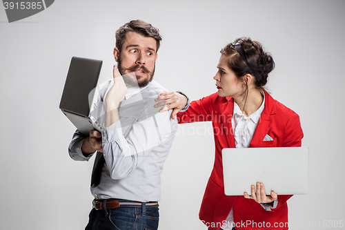 Image of The young businessman and businesswoman with laptops communicating on gray background