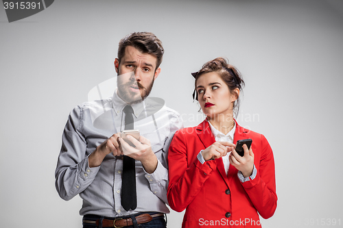Image of Business concept. The two young colleagues holding mobile phones on gray background