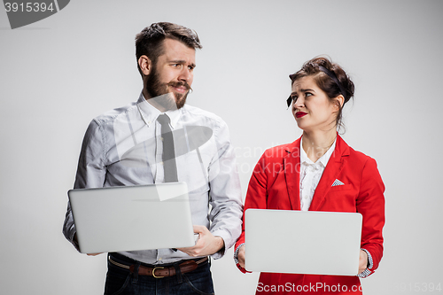 Image of The young businessman and businesswoman with laptops communicating on gray background