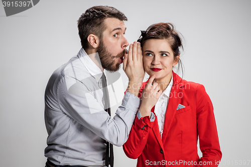 Image of Young man telling gossips to his woman colleague at the office