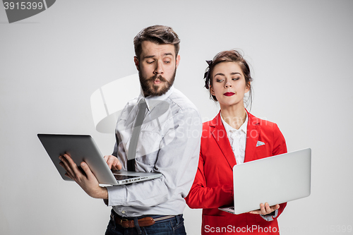 Image of The young businessman and businesswoman with laptops communicating on gray background