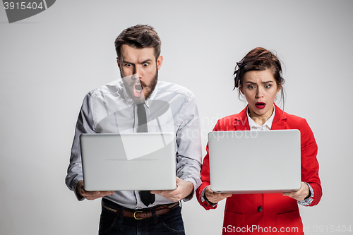 Image of The young businessman and businesswoman with laptops communicating on gray background