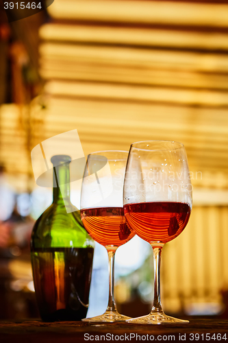 Image of two glasses filled with red wine and bottle in background