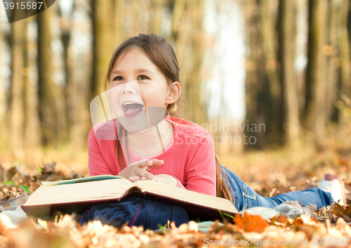 Image of Little girl is reading a book outdoors