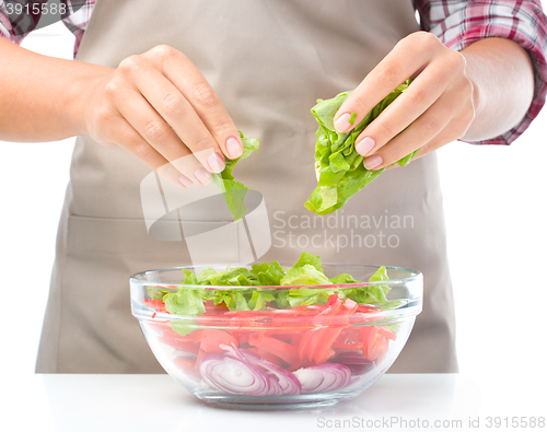 Image of Cook is tearing lettuce while making salad