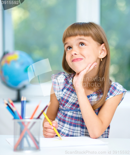 Image of Little girl is drawing using color pencils