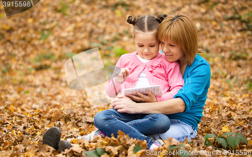 Image of Mother is reading from tablet with her daughter