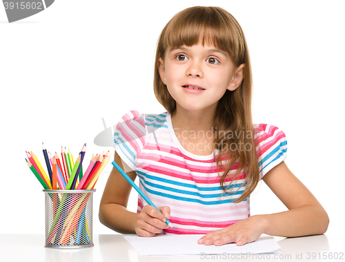 Image of Little girl is drawing using pencils