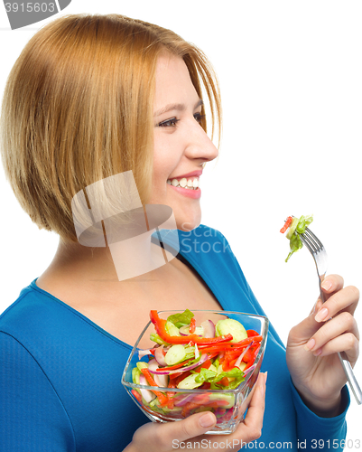 Image of Young attractive woman is eating salad using fork