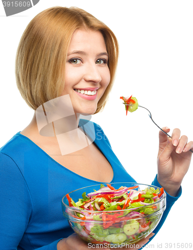 Image of Young attractive woman is eating salad using fork