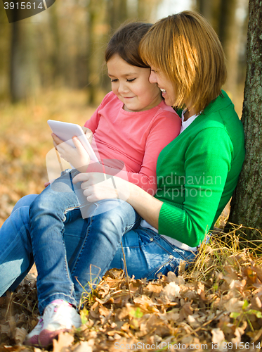 Image of Mother and her daughter is playing with tablet
