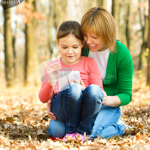 Image of Mother and her daughter is playing with tablet