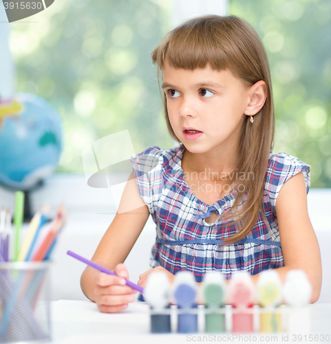 Image of Little girl is painting with gouache