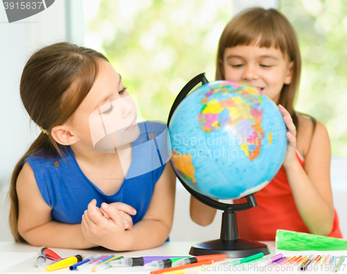 Image of Little girls are examining globe