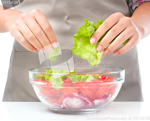 Image of Cook is tearing lettuce while making salad