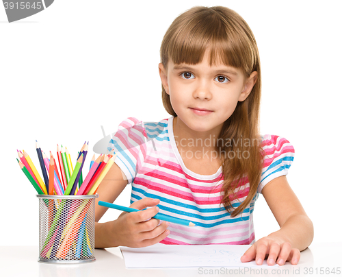 Image of Little girl is drawing using pencils