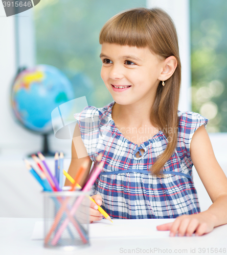 Image of Little girl is drawing using pencils