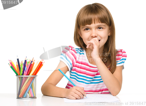 Image of Little girl is drawing using pencils