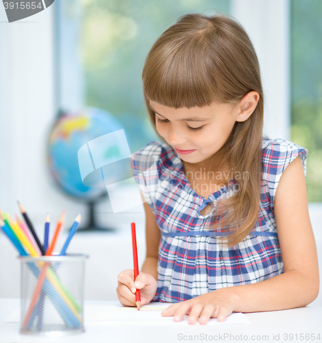 Image of Little girl is drawing using pencils