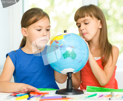 Image of Little girls are examining globe