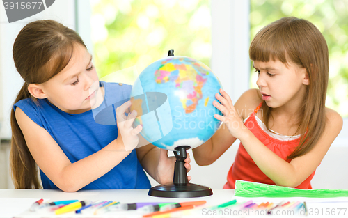 Image of Little girls are examining globe