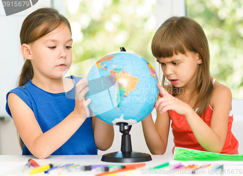 Image of Little girls are examining globe