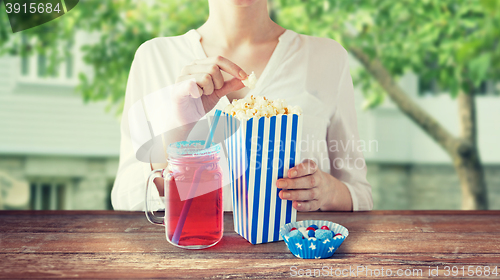 Image of woman eating popcorn with drink in glass mason jar