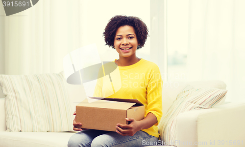 Image of happy african young woman with parcel box at home