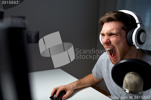 Image of man in headset playing computer video game at home