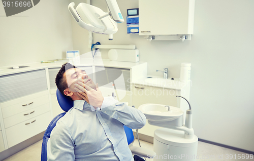 Image of man having toothache and sitting on dental chair